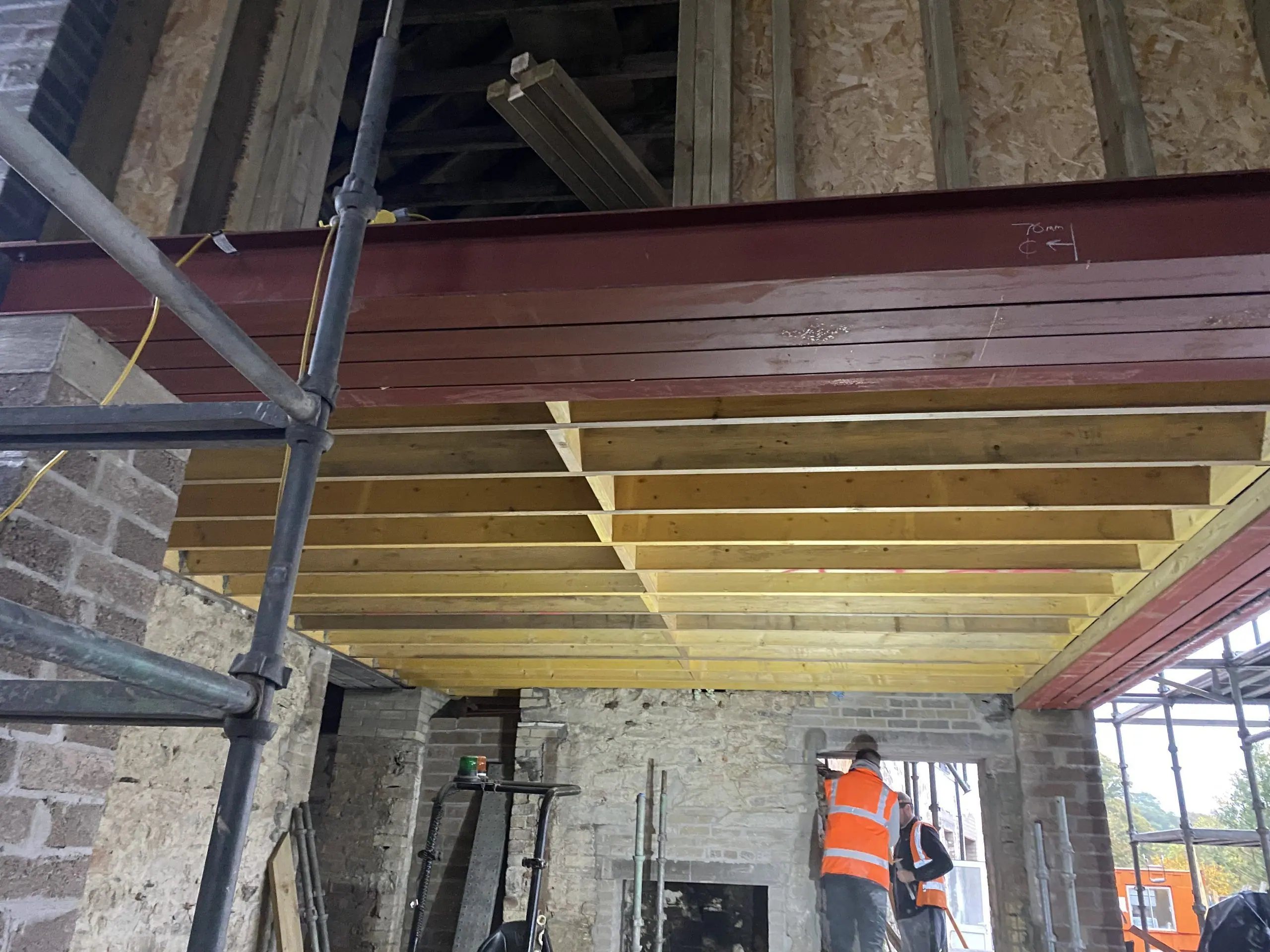 New steel beams and timber joists supported on props inside the stone walls